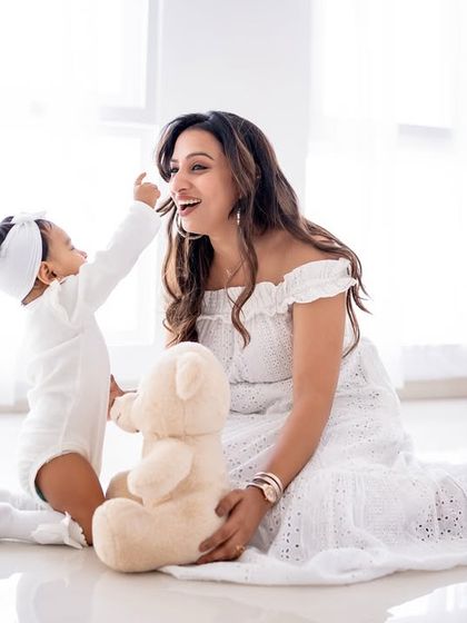 A mother and daughter playing together on the floor with a teddy bear.