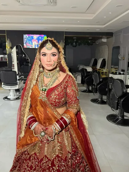 A full view of this bride's stunning look in our salon. The makeup is perfectly balanced with her heavy jewellery and the rich colors of her lehenga, creating a harmonious and royal appearance.