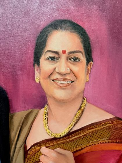 A close-up of the mother from a family portrait, capturing her warm smile and the beautiful details of her saree and jewelry.