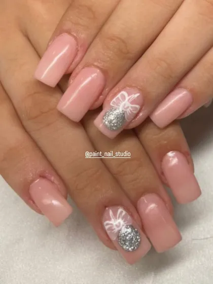A soft and pretty Christmas design. This set uses a milky pink base with accent nails featuring a silver glitter ornament设计 and a delicate white bow.