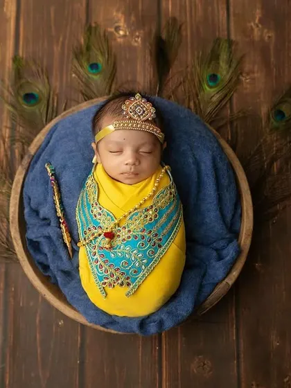 Our little Krishna, peacefully sleeping. This Janmashtami-themed newborn shoot uses rich colors, peacock feathers, and traditional details to create a divine portrait.