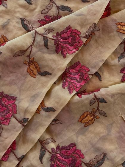 This organza fabric features a bold, artistic rose pattern. The deep magenta and muted gold threads create a vintage-inspired design that would make a stunning custom jacket or a unique saree.