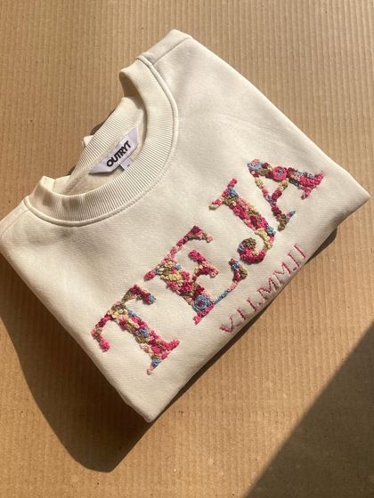 The 'TEJA' floral name sweatshirt, captured in beautiful sunlight that highlights the texture of the hand embroidery.