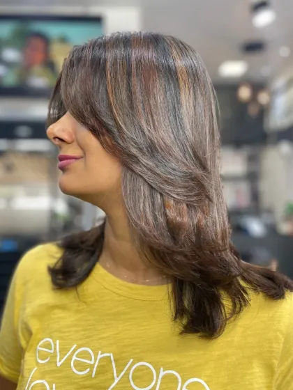 A layered haircut with stylish bangs and subtle highlights. This is a modern and chic look that perfectly frames the face.