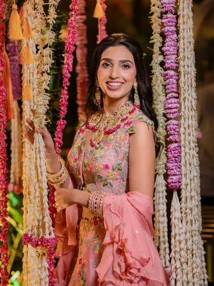 A beautiful indoor Mehendi setup, transforming the space with pastel lounges, marigold accents, and traditional garlands for a "pooja to party" vibe.