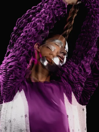 A creative motion shot highlighting the long rope braid and the metallic makeup, giving a sense of otherworldly movement.