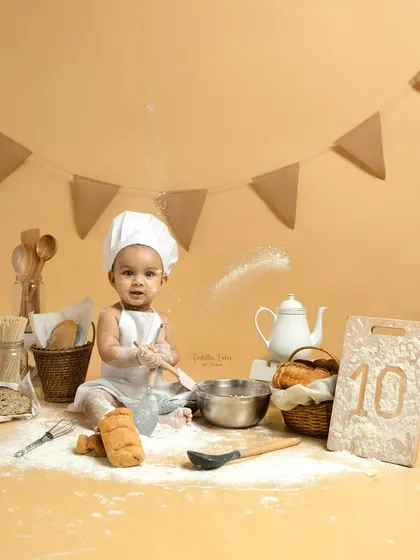 A wider view of the 'Baby Chef' set, complete with a tiny teapot, bread baskets, and a sign marking the baby's 10-month milestone. Every detail is thoughtfully arranged for a perfect shot.