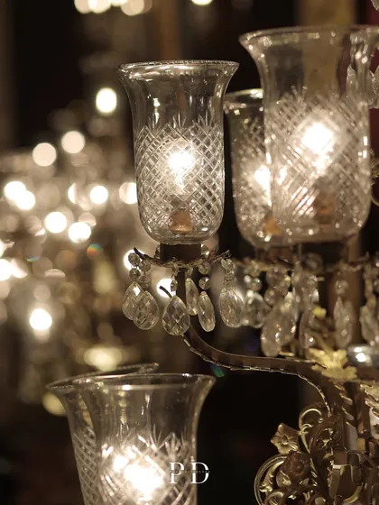 A close-up of a vintage-style standing glass chandelier. The intricate crystal work and warm light add a touch of old-world charm and sophistication to any event.
