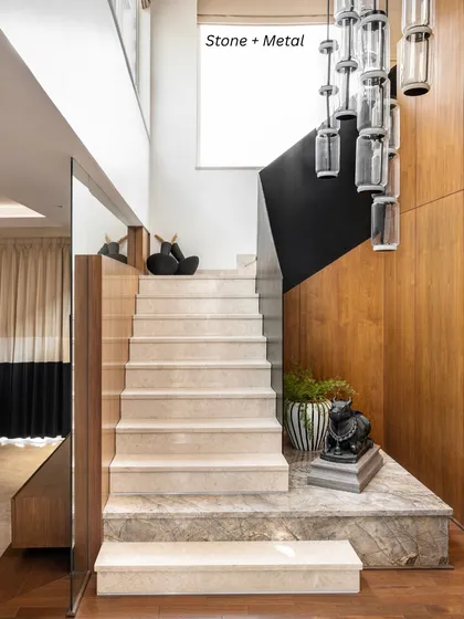 Stone + Metal: This combination offers timeless impact. Here, a marble staircase is paired with a modern metal chandelier, creating a look that is both classic and contemporary.