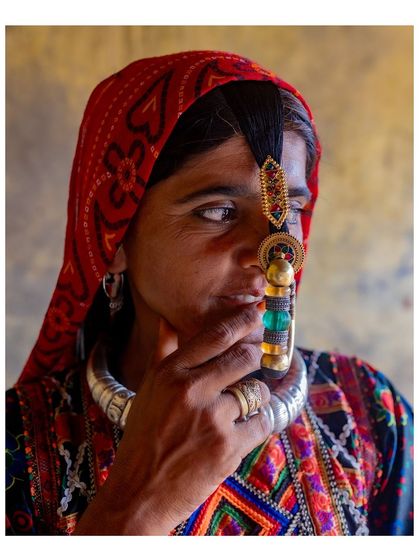 A stunning close-up of a Dhaneta Jat woman, focusing on her traditional nose ring and silver necklace. The rich colors and textures of her attire are beautifully captured.