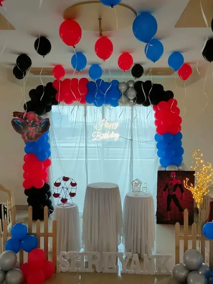 A Spiderman theme for a home celebration, featuring a balloon arch, hanging balloons, and character props.