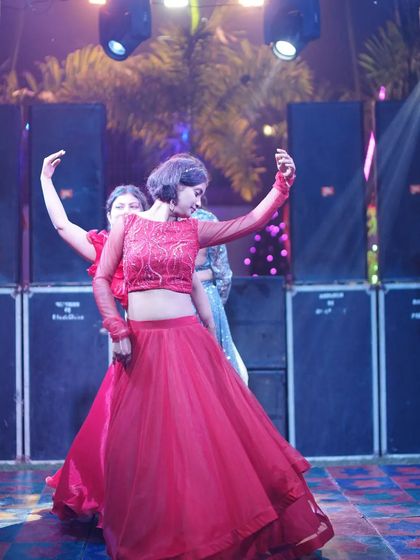 A graceful pose from a sister's solo dance. Her red lehenga looks stunning under the stage lights.