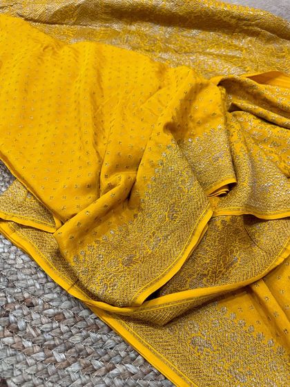 The full drape of the yellow Banarasi silk saree, showing the beautiful fall of the fabric and the contrast between the butti work and the heavy border.