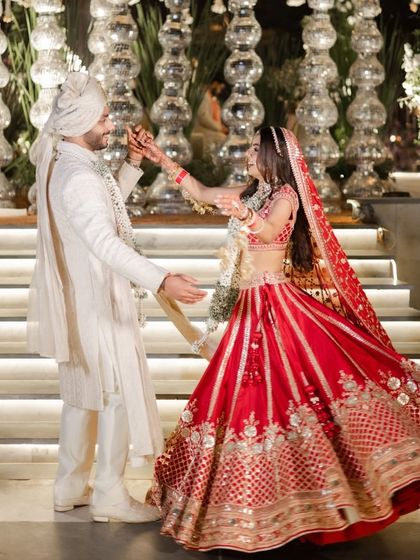 A playful moment captured during the wedding ceremony, as the bride and groom share a dance, their red and white outfits creating a striking contrast.