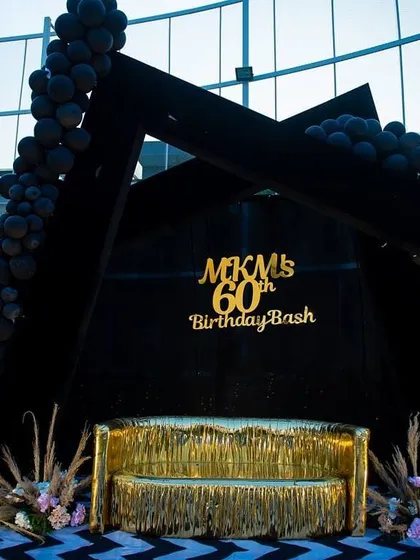 The custom-built stage for the 60th birthday bash, featuring a geometric frame and a gold fringe sofa.
