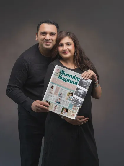A creative pregnancy announcement. The couple holds a custom newspaper headline, "Blooming Beginning," sharing their joy in a unique and personal way. It's a fun prop that tells their story perfectly.