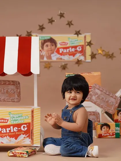 Capturing a moment of pure joy as the baby girl claps her hands during her Parle-G themed session.