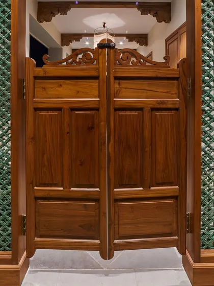 Inspired by my travels in Morocco, these wooden salon doors create a distinctive demarcation for a passage area. Paired with green ceramic *jali* on the sides, they allow for ventilation and create a beautiful play of shadows, bringing a touch of Moroccan style into the home.