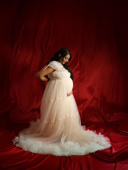 A full-length view of our cream gown against a red backdrop, showcasing the contrast and elegance of the setup.