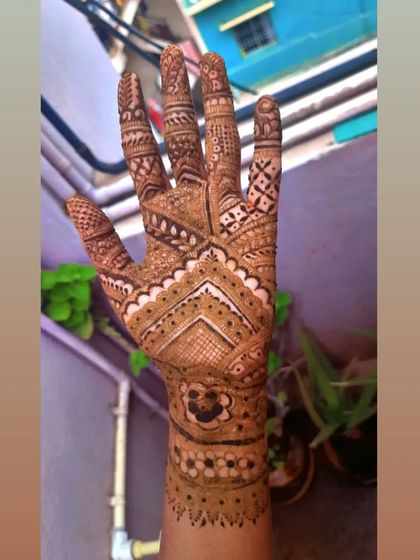 This design uses negative space to make the geometric patterns pop. The clean chevron lines on the back of the hand create a modern feel within a traditional bridal framework.