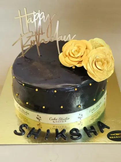 A classic and elegant chocolate truffle cake. The dark chocolate glaze is decorated with two beautiful yellow sugar flowers and a "Happy Birthday" ribbon.