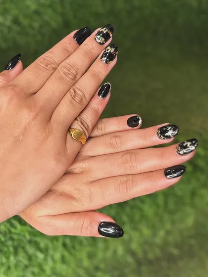 A full view of both hands, displaying the balance between the solid black nails and the detailed foil accent nails.