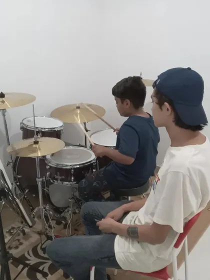 A close-up of a drum lesson, showing the hands-on teaching approach.