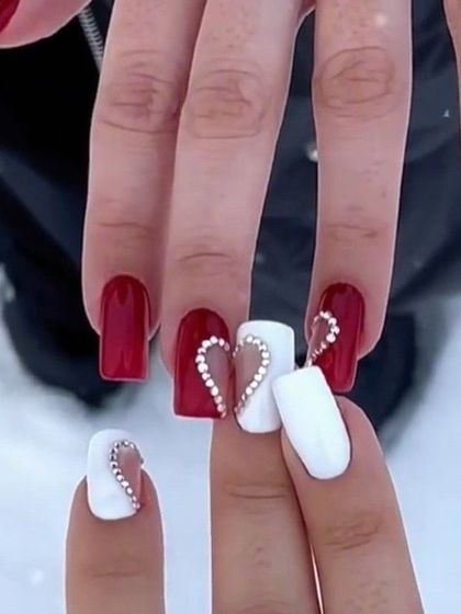 A cute Valentine's Day idea with red and white nails and a sparkling rhinestone heart.
