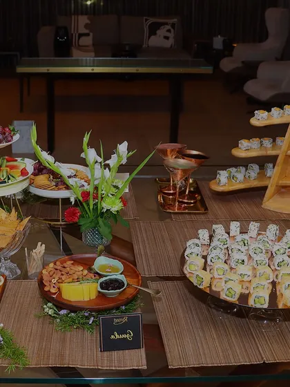 A full view of a beautifully arranged grazing table, combining sushi platters with cheese boards and other appetizers for a complete cocktail party solution.