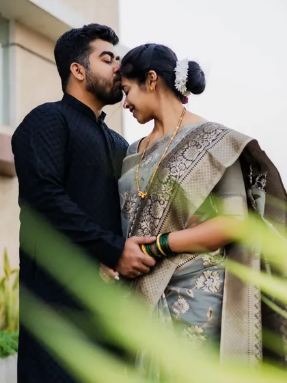 A sweet forehead kiss, framed by natural greenery. This is a classic pose for a reason, it's full of tenderness and love.