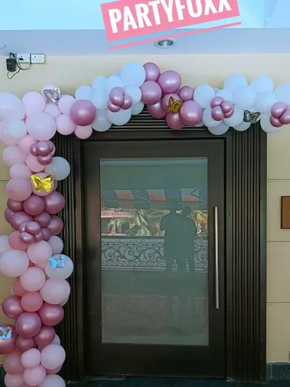 A welcoming entrance decoration with a pink and white balloon arch, adding a festive touch to the party venue from the very first step.