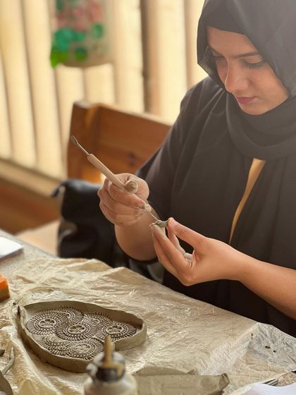 A participant from a corporate event carefully crafting a heart-shaped tray. Hand-building allows for so much personal expression, making it a great activity for team building.