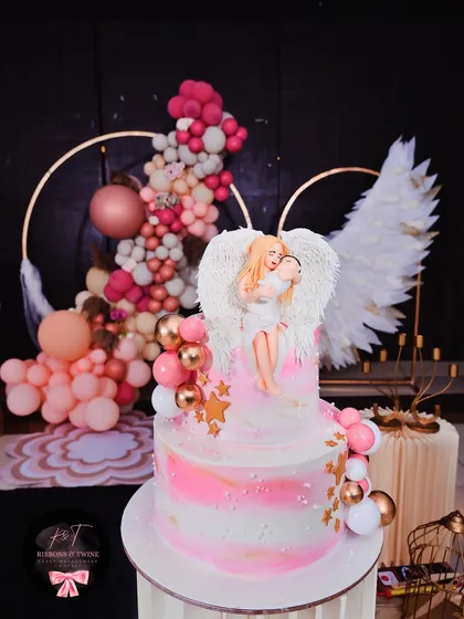 The stunning baptism cake, featuring an angel holding a baby, perfectly coordinated with the 'Angel Wings' theme of the event.