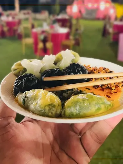 A guest holds a plate of our assorted dim sum at an outdoor wedding event. This image captures the experience of enjoying our gourmet food in a beautiful, celebratory setting.