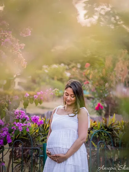 The quiet beauty of motherhood. This serene maternity portrait, set in a garden, captures the gentle anticipation and love a mother feels, using soft natural light to create a dreamy, painterly effect.