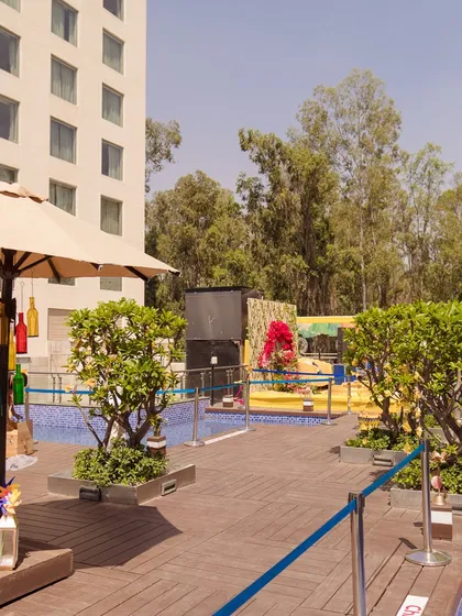 A wide shot of the poolside Haldi venue, showing the main stage and the custom green photo wall in the background.