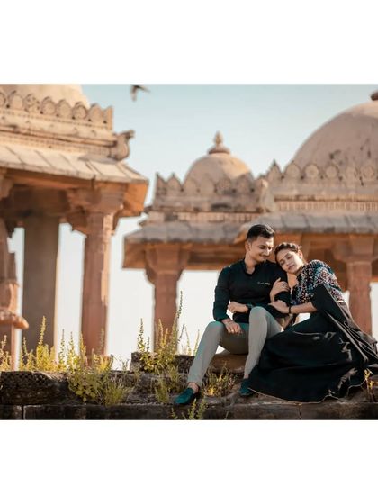 A quiet moment of togetherness for a couple during their pre-wedding shoot, seated among ancient stone cenotaphs under the warm sun.