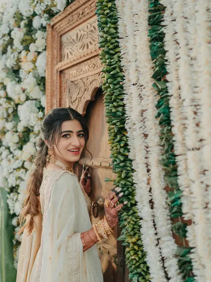 The bride poses against a beautiful floral wall, her smile radiant. I ensure the decor provides stunning backdrops for bridal portraits.