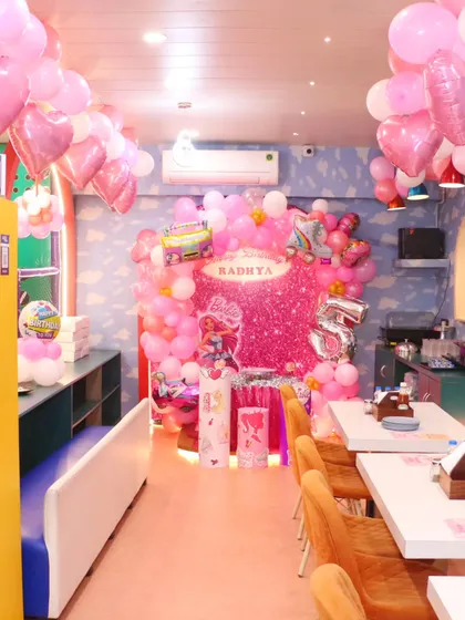A full view of our Barbie-themed party dining area, decorated with sparkling pink backdrops and heart-shaped balloons. I make sure the entire space feels magical.