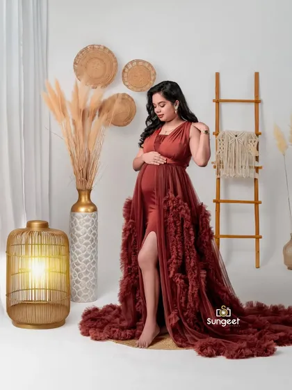 A full-length standing pose that showcases the elegant design and flowing train of the rust-colored gown.