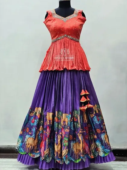 A vibrant combination of a purple Kalamkari skirt and a peach-colored peplum blouse.