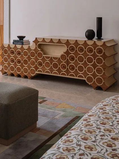 This is 'Brutus,' our handcrafted TV unit. The design features a repeating circular pattern inlaid into the wood, with a unique scalloped profile. It’s a piece that hides technology behind a beautiful, sculptural facade.