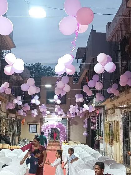 An outdoor venue decorated for a butterfly theme, with purple balloon bunches hanging overhead.