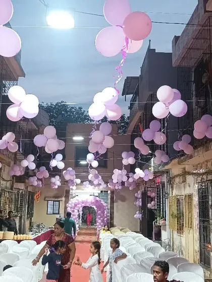 An outdoor venue decorated for a butterfly theme, with purple balloon bunches hanging overhead.