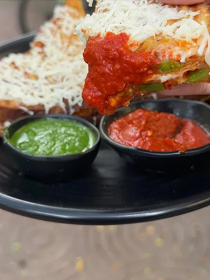 Dipping a piece of my Melting Sandwich into a spicy red sauce. It's a flavour explosion in every bite.