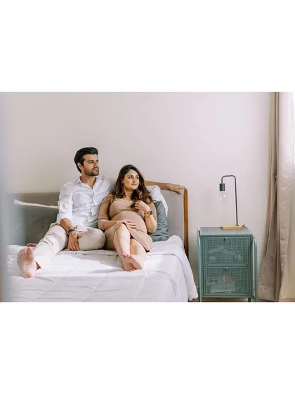 A relaxed portrait of the couple sitting on their bed. This kind of unposed, lifestyle photography is perfect for capturing the quiet, everyday moments of waiting for baby.