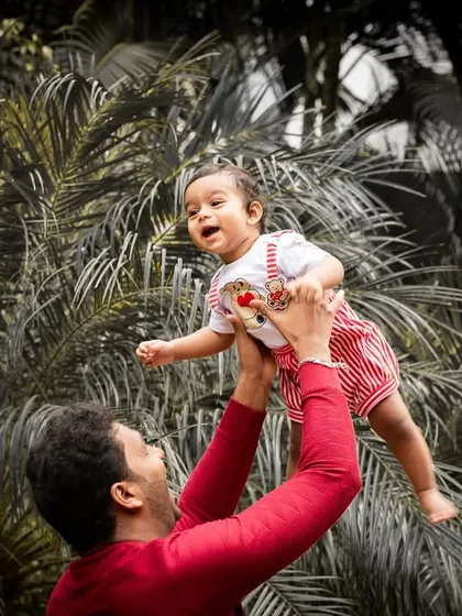 A father playfully lifts his baby into the air. This dynamic shot, with its selective color treatment, creates a powerful and artistic family portrait.
