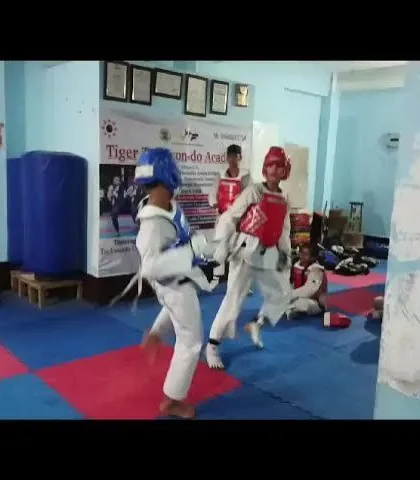 Two students engaged in a sparring match at our academy. They are wearing full Kyorugi gear, including chest guards and helmets, for safety.