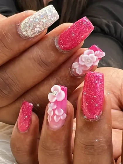 A detailed shot of the sculpted 3D flowers on a pink glitter base.