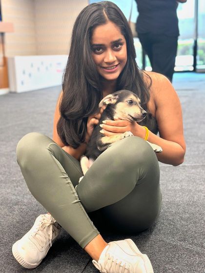 A happy participant smiles for the camera while holding a small, adorable black and white puppy after a rewarding yoga session.